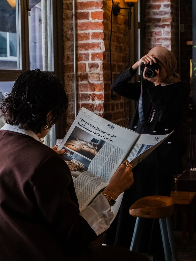 A reader holding a printed Gawlo Brief at a sunlit window in Lisbon, early morning.